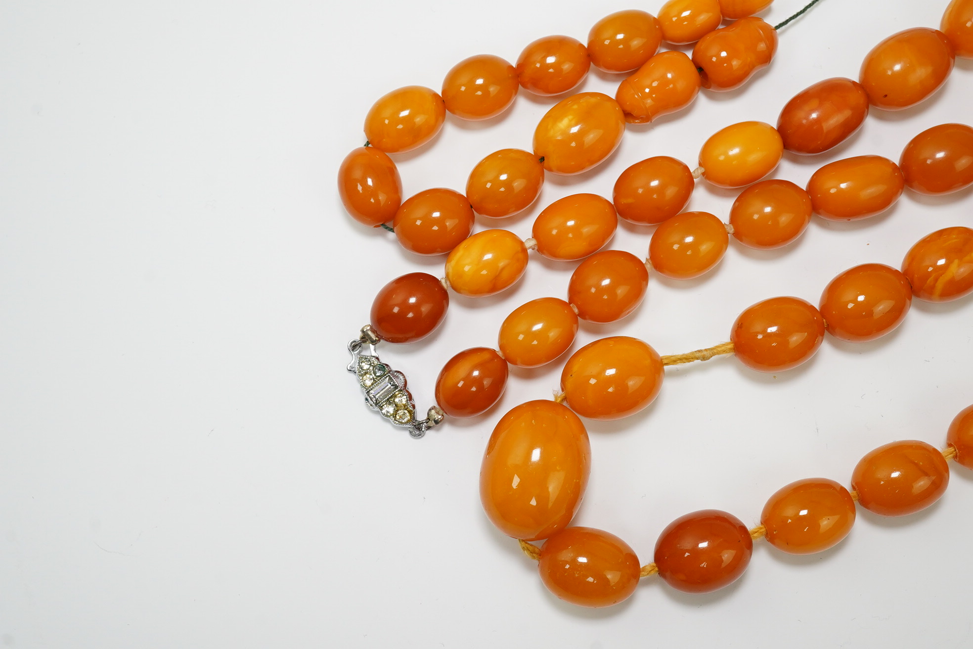 Two single strand graduated oval amber bead necklaces, longest 70cm, and a small group of amber beads strung as a bracelet